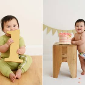 one-year-old baby girl holding number one, smiling at smash cake