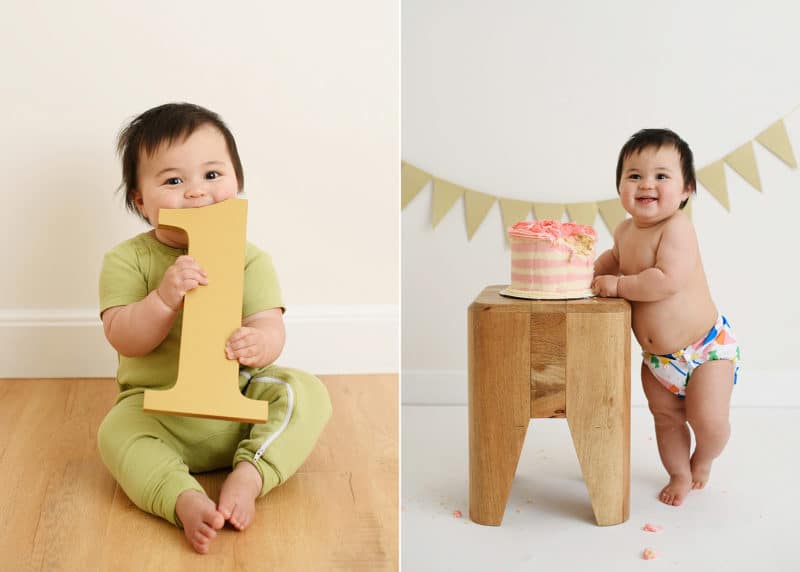 one-year-old baby girl holding number one, smiling at smash cake