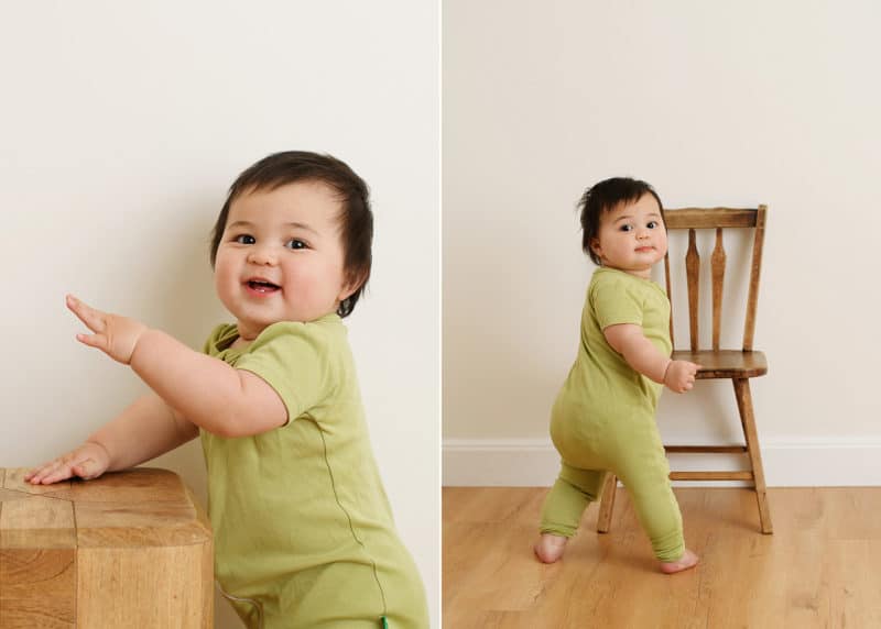 one year old baby girl balancing on chair, smiling