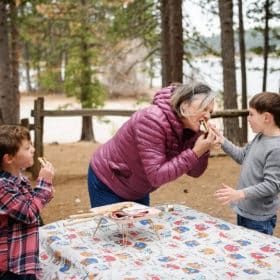 mom and two sons eating smores while camping