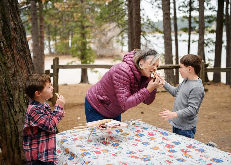 mom and two sons eating smores while camping