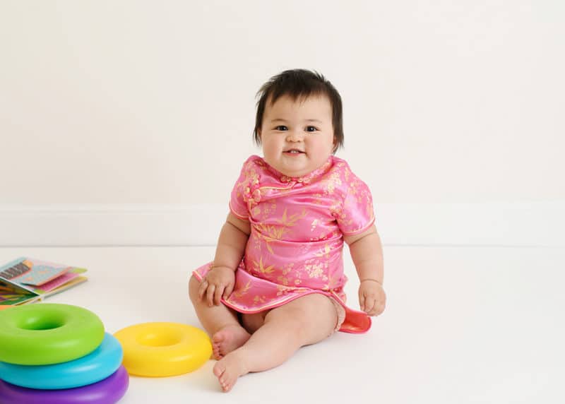 one year old baby girl in traditional dress with toys