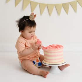 one year old girl looking at smash cake studio shoot