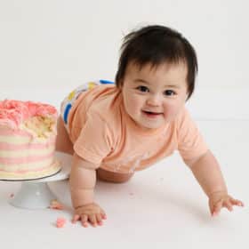 one year old baby girl crawling with smash cake