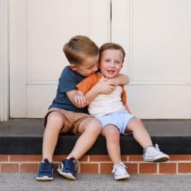 two brothers hugging and smiling in front of a brick building in old sacramento california