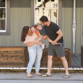 family of four hugging and smiling in front of old train car sacramento california