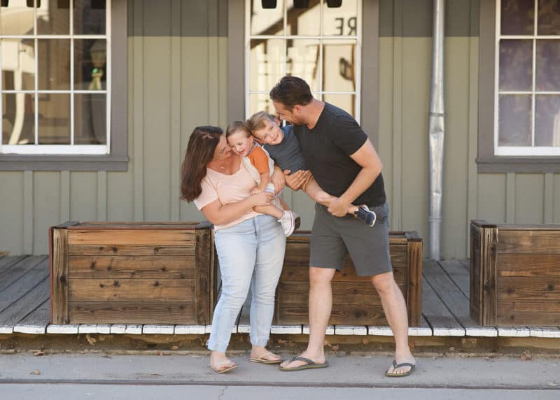 family of four hugging and smiling in front of old train car sacramento california