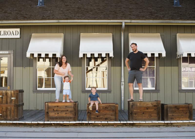 family of four standing on wooden boxes in front of old train car in sacramento california