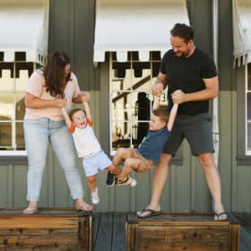 mom and dad swinging young boys in front of train car in old sacramento california