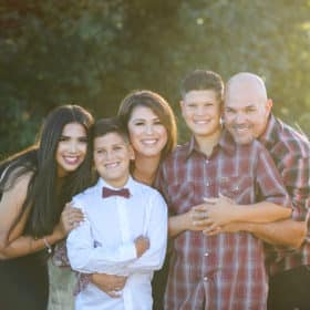 family of five smiling outdoors during golden hour