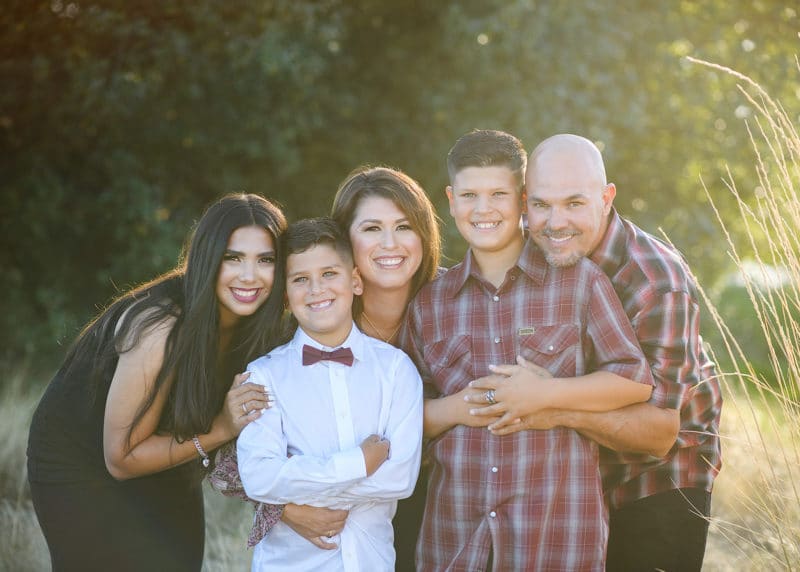 family of five smiling outdoors during golden hour