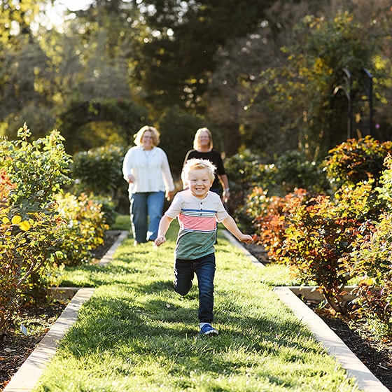 young boy running in the garden with moms following behind sacramento california