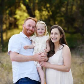 mom and dad with young girl during maternity photo shoot