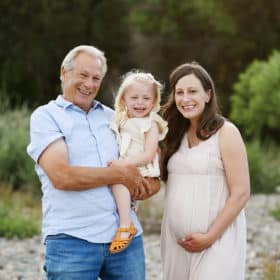 pregnant woman with dad and daughter posing by the river