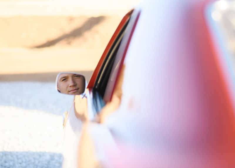 teenage boy looking in the rearview mirror of a classic chevy camero