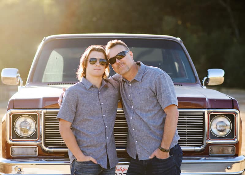 dad and son posing in front of classic truck with sunglasses on