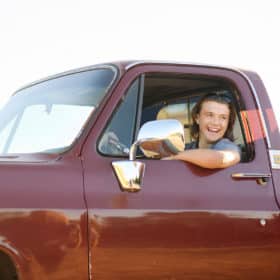 teenage boy in the drivers seat of classic truck smiling