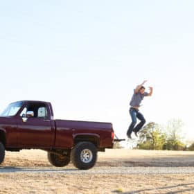 teenage boy jumping out of old truck bed to dad in rescue california