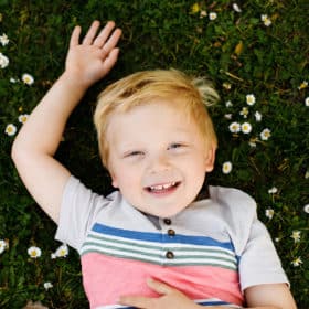 young boy posing in grass with flowers in sacramento california
