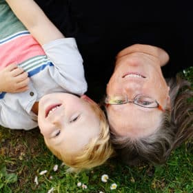 boy and mom smiling laying on the grass in spring time natural light