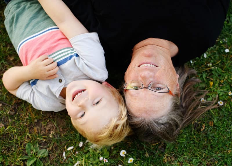 boy and mom smiling laying on the grass in spring time natural light