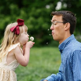 young girl blowing dandelion in dad’s face funny sacramento california