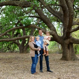 family of four posing in the trees during spring sacramento california
