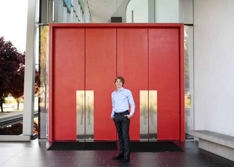 high school senior boy posing with red doors sacramento california