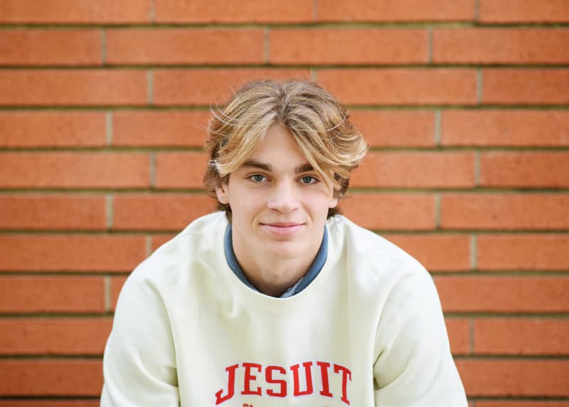 high school senior boy smiling in front of a brick wall sacramento california