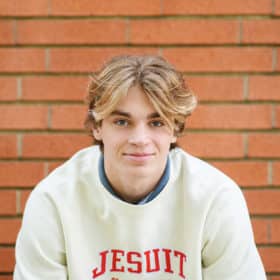 high school senior boy smiling in front of a brick wall sacramento california