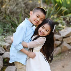 brother and sister hugging, laughing together outdoors in sacramento california