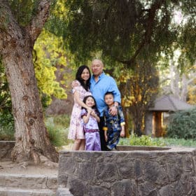 family of four posing outdoors under a tree in springtime sacramento california