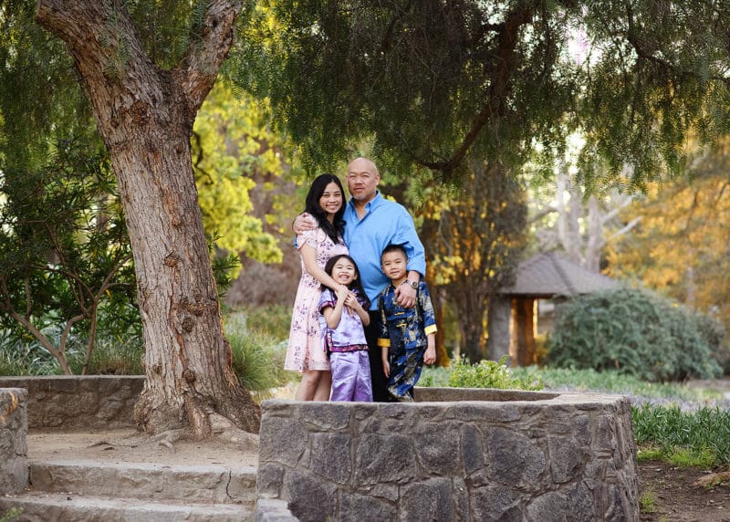 family of four posing outdoors under a tree in springtime sacramento california
