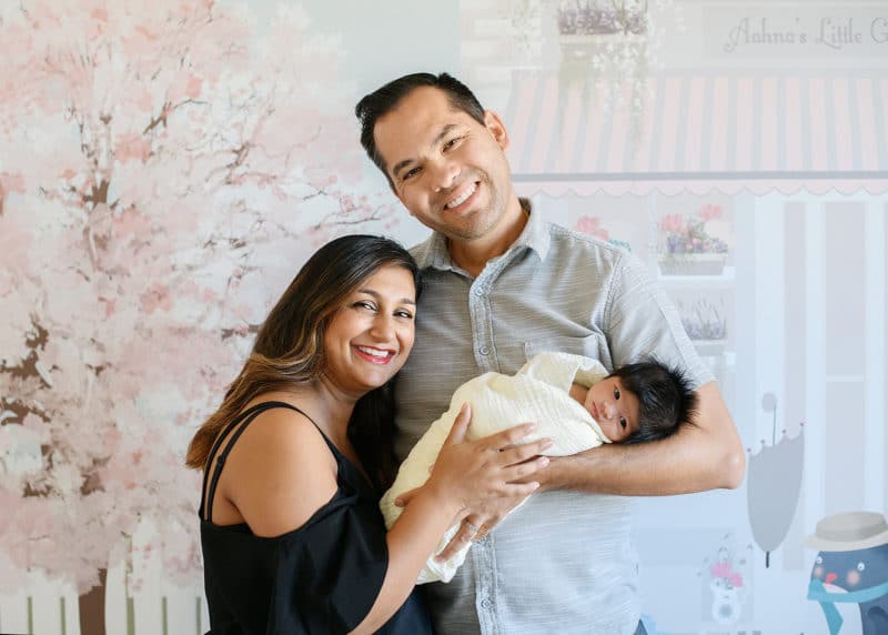 mom and dad with newborn baby girl in home nursery