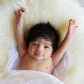 newborn baby girl laying with her arms up above her head