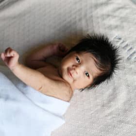 newborn baby girl smiling at the camera in at home photo session
