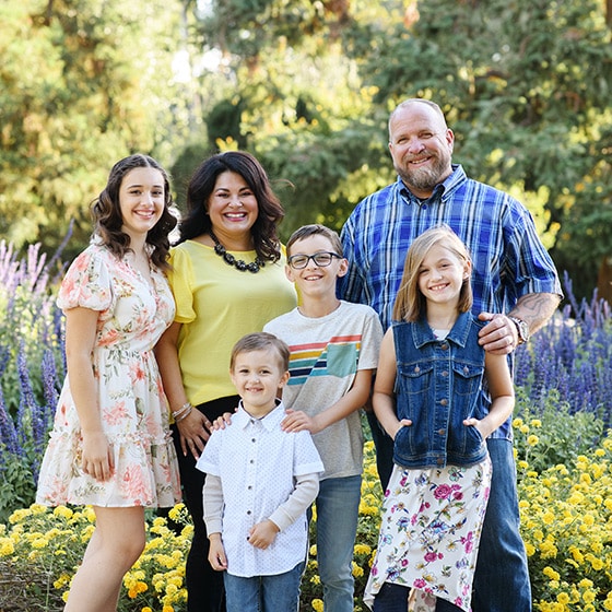 mom and dad with four kids posing in front of wildflower patch in sacramento california