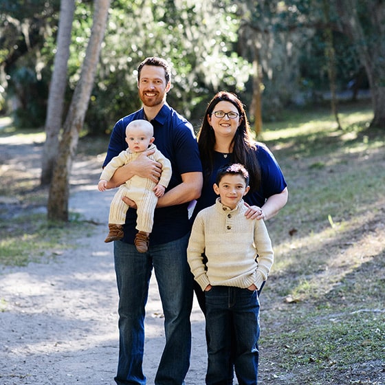 family of four smiling together on a natural path in tampa florida