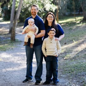 family of four smiling together on a natural path in tampa florida