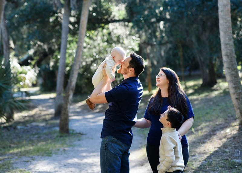 dad kissing baby, mom and son looking on natural light family photo