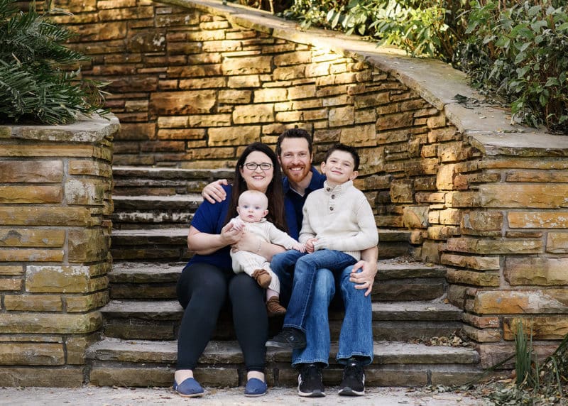 family of four sitting on stone steps in outdoors natural light florida