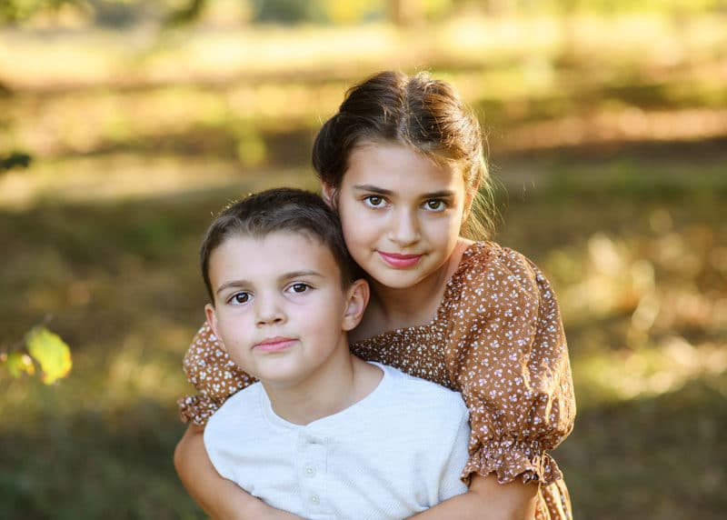 brother and sister hugging in the park in natural light davis california
