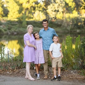 family of four standing by a pond in the park during summer in davis california