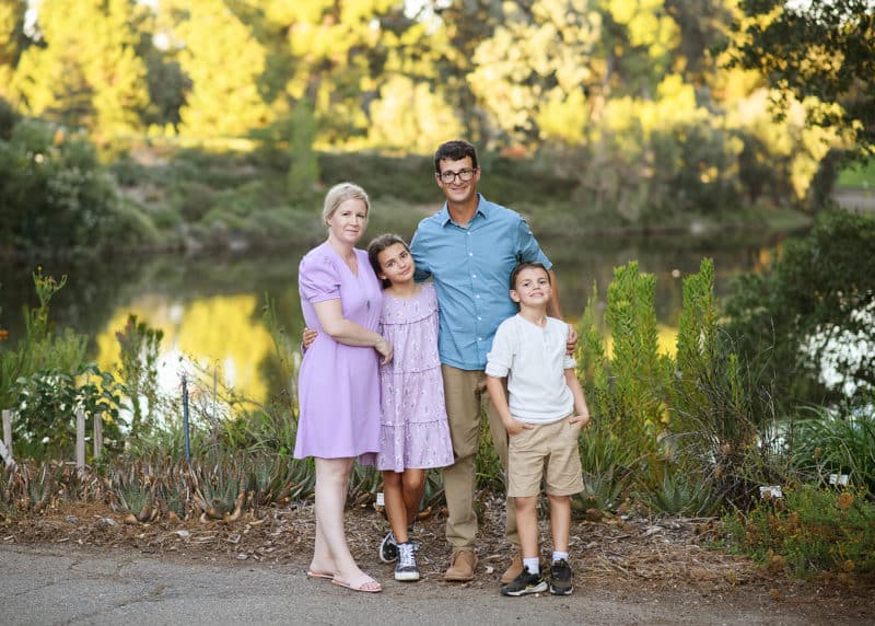 family of four standing by a pond in the park during summer in davis california