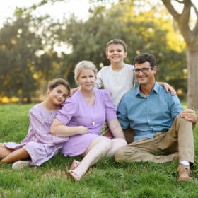 young family sitting on the grass under a tree during summer in davis california
