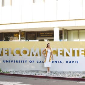 college graduate standing in front of welcome center at uc davis