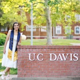 graduation pictures with young woman leaning on UC Davis brick sign