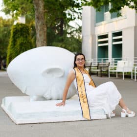 taking graduation photos at UC Davis with stole in front of statue