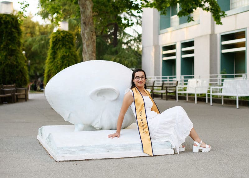 taking graduation photos at UC Davis with stole in front of statue