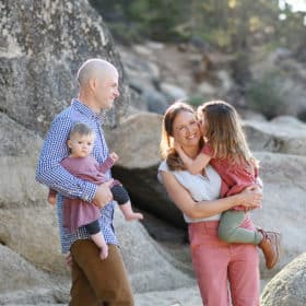 toddler girl kissing mom on the cheek, dad holding baby girl on the shores of lake tahoe